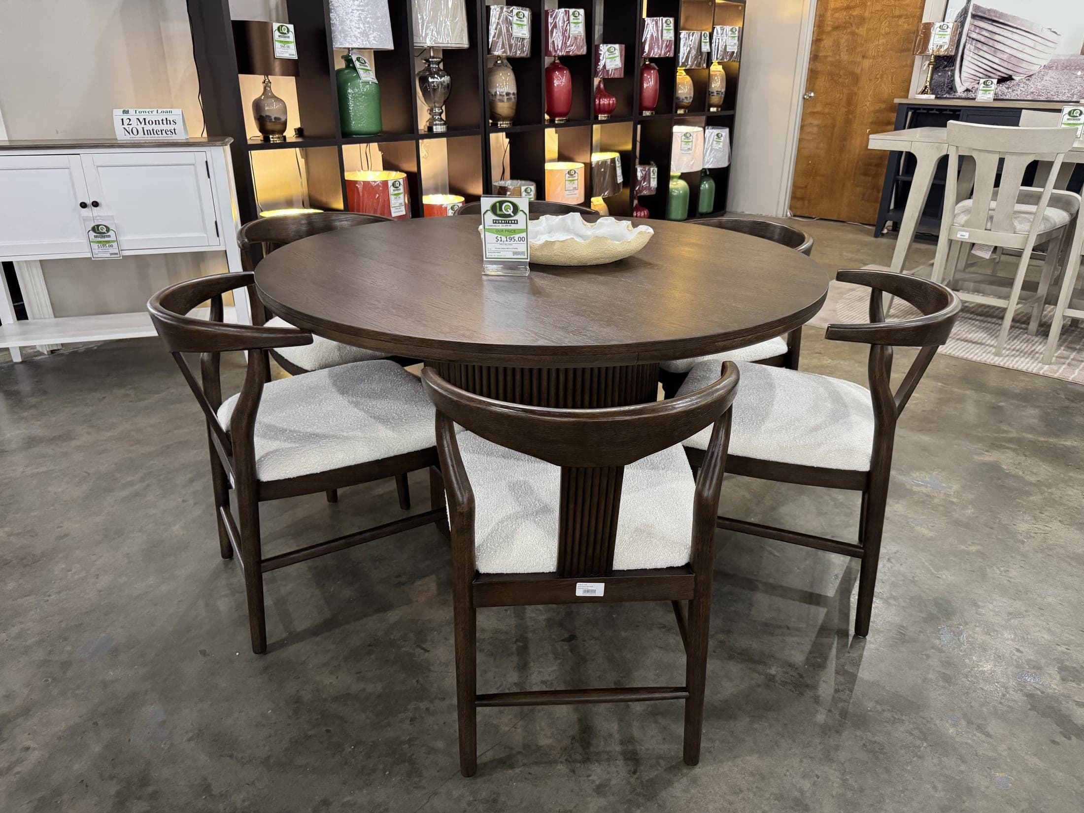 Round dark-finish dining table with cream upholstered chairs