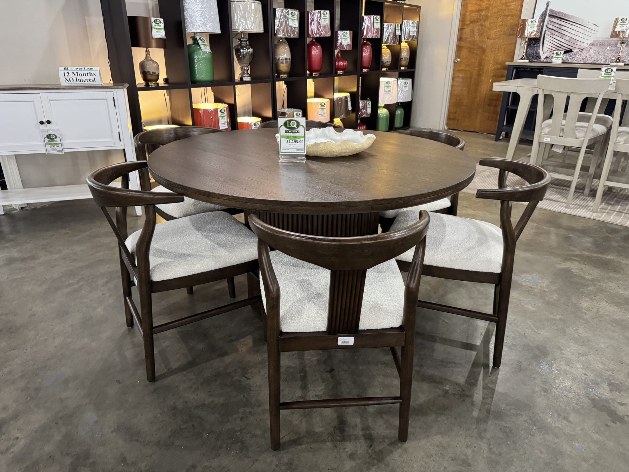 Round dark-finish table with cream upholstered chairs