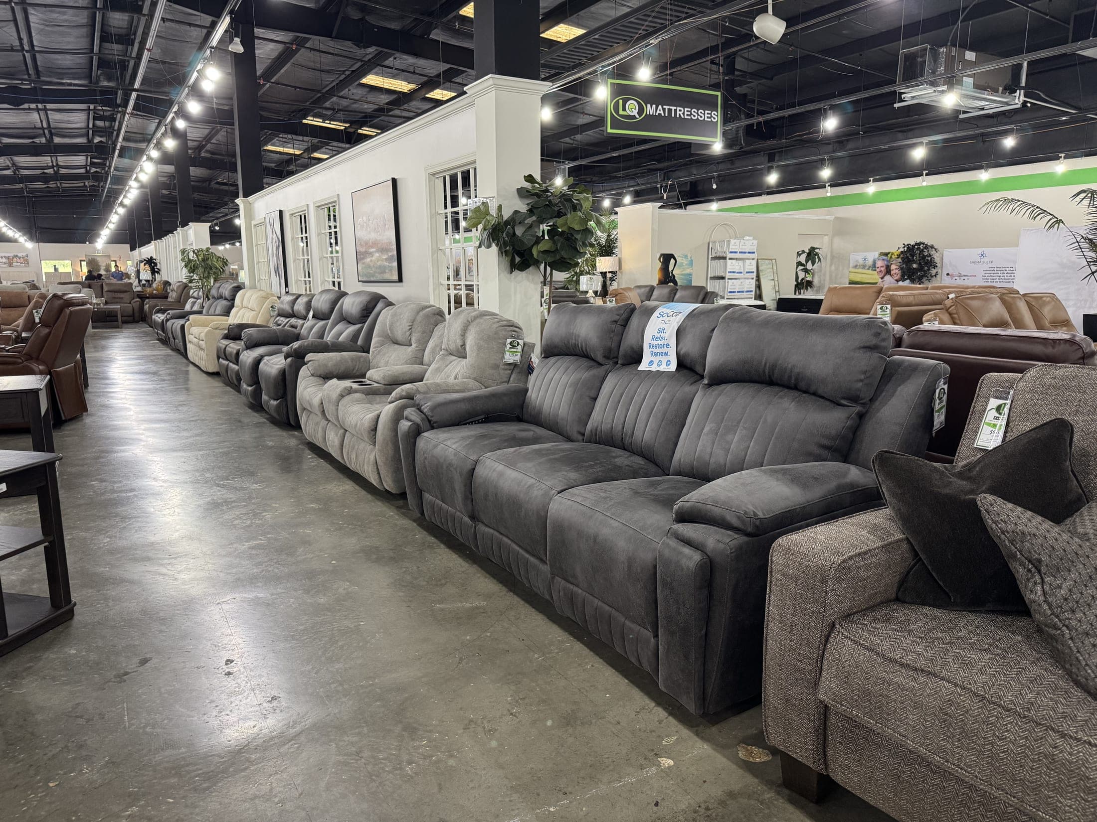 Rows of gray reclining sofas down a warehouse aisle