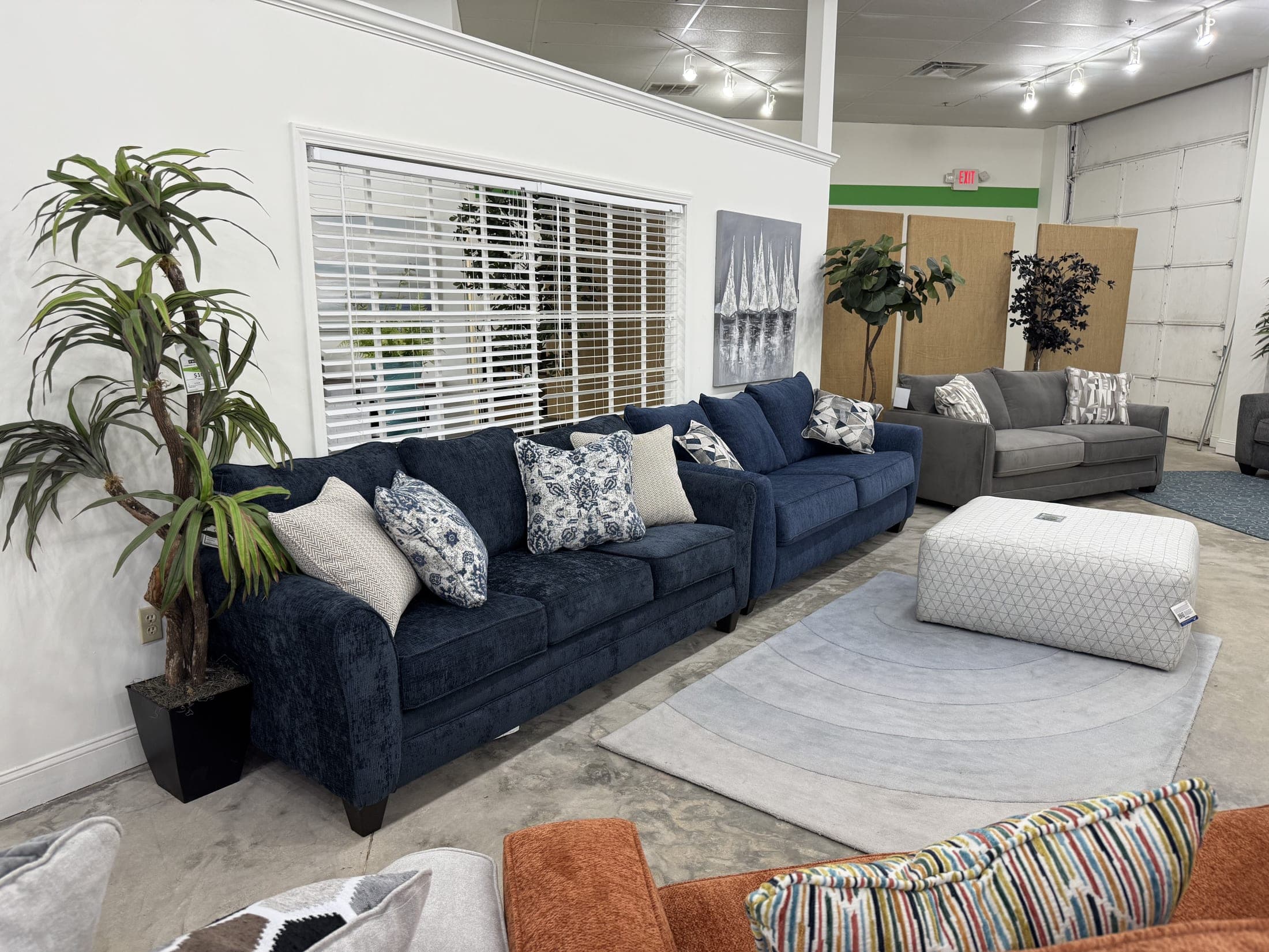 Navy blue upholstered sofa with accent pillows and a white ottoman